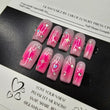 Pink nail art designs on a black tray with a white background