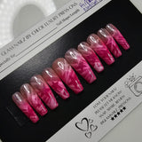 Pink and clear nail extensions on a black and white packaging with a ring light in the foreground.