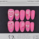 Set of pink press-on nails with heart designs on a black card with branding text.
