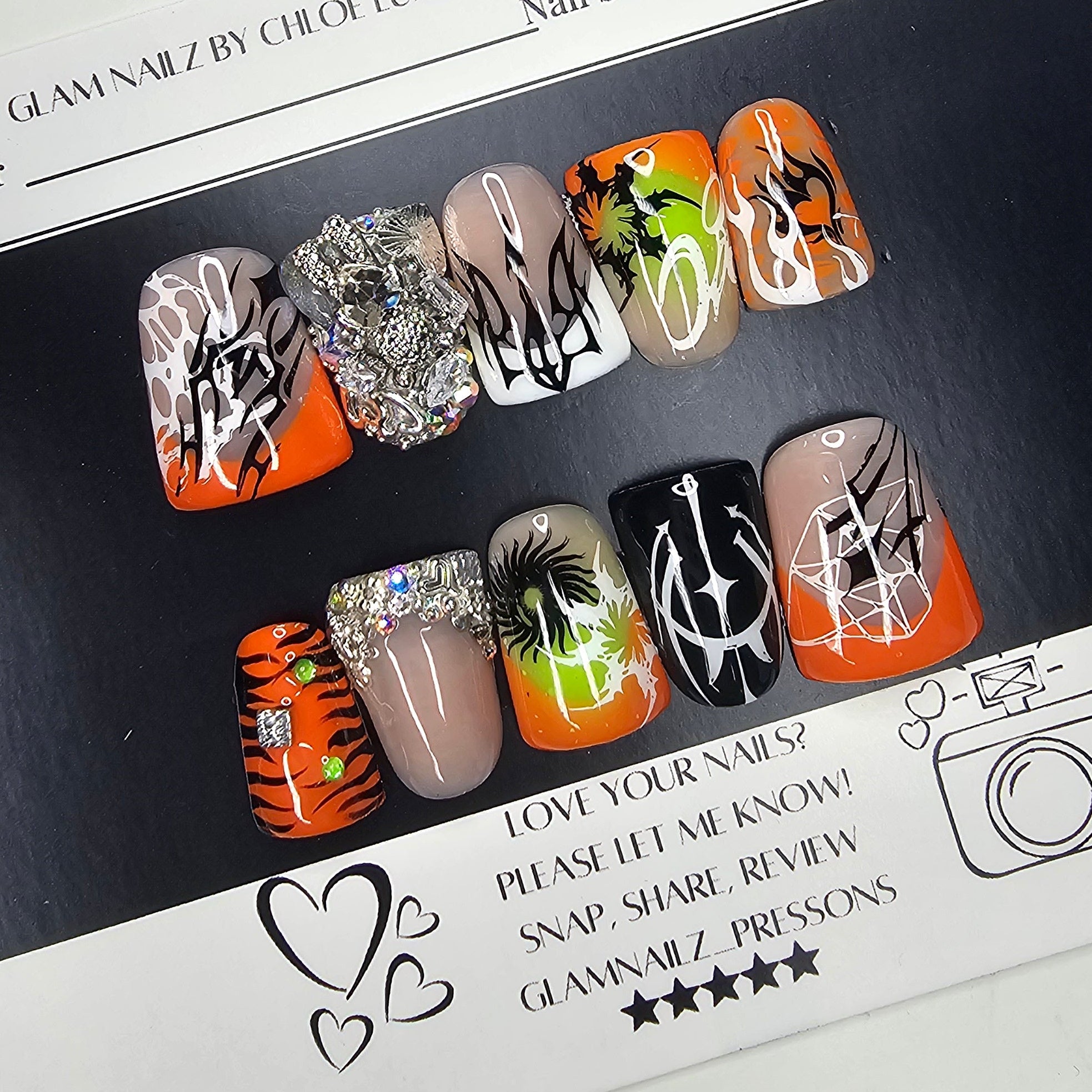 Set of nail art samples with various designs on a black card, featuring a visible brand logo.
